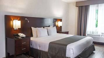 Habitación de hotel con una cama grande, dos mesitas de noche con lámparas, un teléfono y un equipo de aire acondicionado.