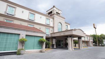 Un hotel con una entrada amplia, varias ventanas y una torre del reloj.