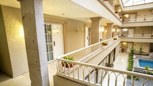 A multi-level hotel interior with a central atrium, a pool area, and multiple balconies with railings. - Best Western Plus Monterrey Colon (Monterrey)