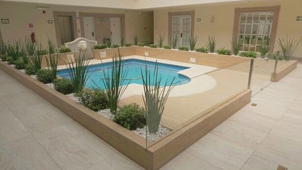 A pool area with a tiled floor, surrounded by planters and a glass barrier. - Best Western Plus Monterrey Colon (Monterrey)