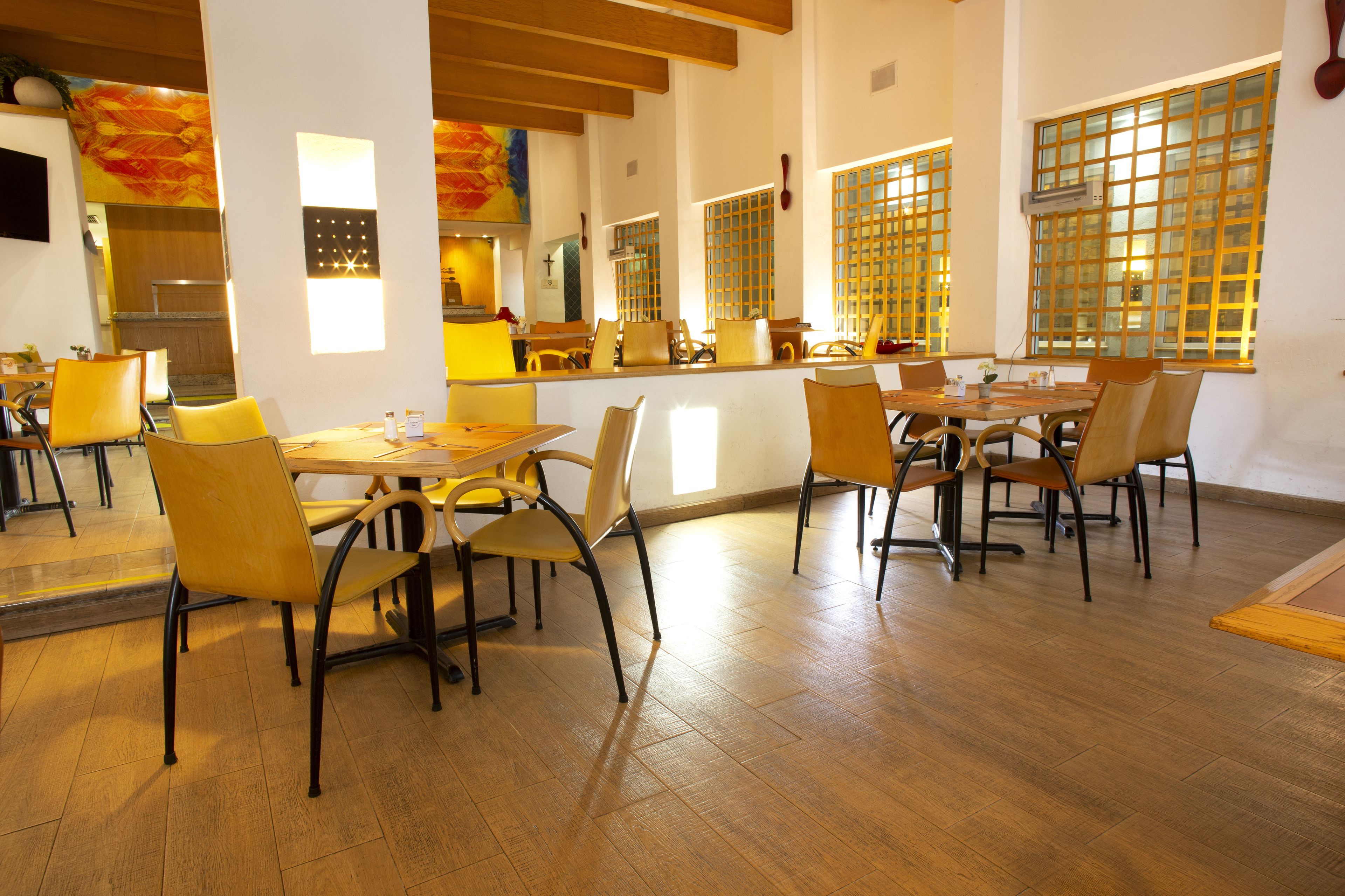 Ein Restaurant mit Holzboden, gelben Stühlen und einer Theke.