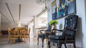 A modern interior with a dining area, leather chairs, a vase with plants, and abstract art on the wall. - Best Western Plus Monterrey Colon (Monterrey)