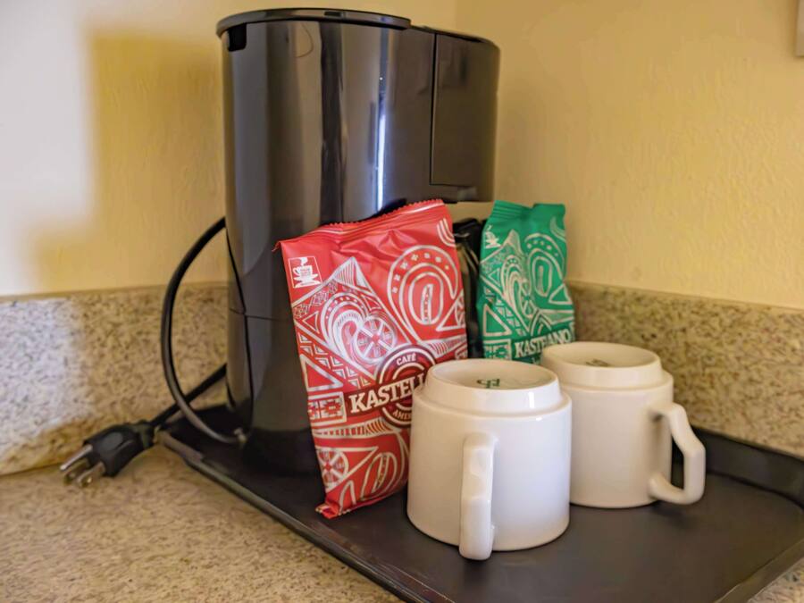 Una cafetera, dos tazas de café y dos cápsulas de café sobre una bandeja.