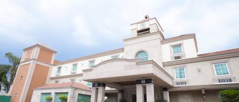 A hotel with a central entrance, multiple balconies, and a clock tower.