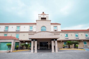 A building with a central clock tower, multiple windows, and a green garage door.