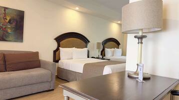 A hotel room with a large bed, a smaller sofa, a table with a lamp, and a painting on the wall.