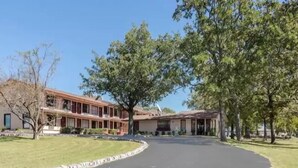 A two-story building with a curved driveway and a lawn in front. - The Parkwood Inn & Suites (Mountain View)