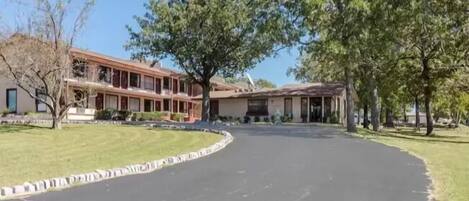 En toetagers bygning med en buet indkørsel og en græsplæne foran.