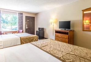 Una habitación de hotel con dos camas, televisión, escritorio y lámpara.