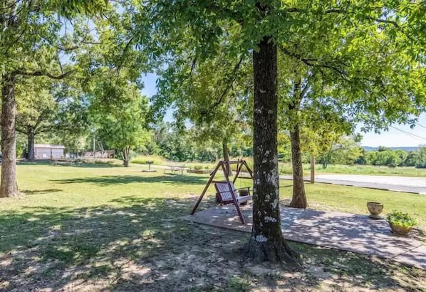 Un parque con un columpio, una mesa de picnic y un sendero pavimentado.