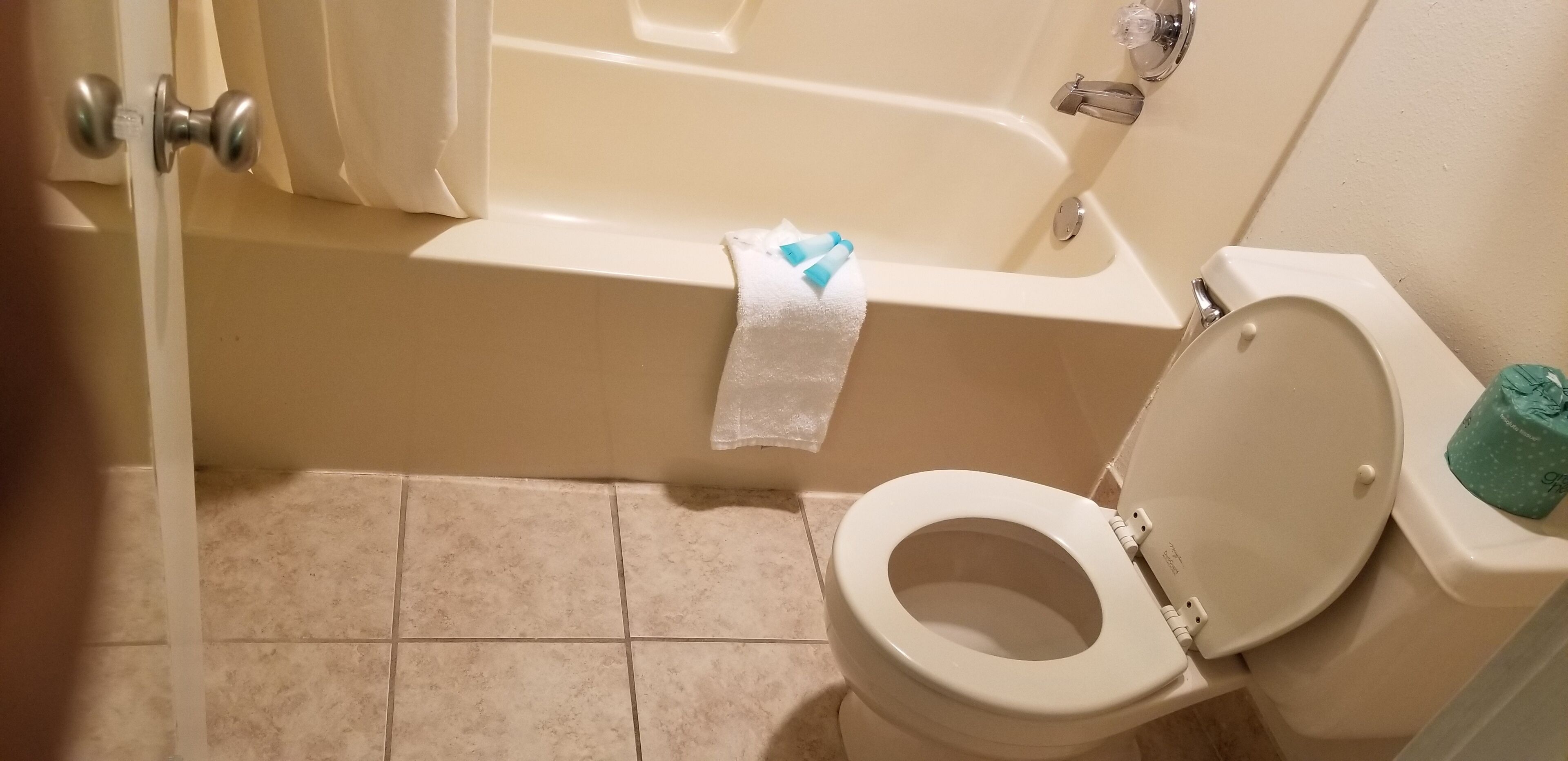 A bathroom with a bathtub, toilet, and a towel on the floor.