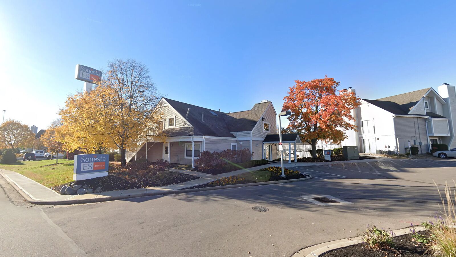 A residential area with houses, a Sonesta ES sign, and autumn foliage.