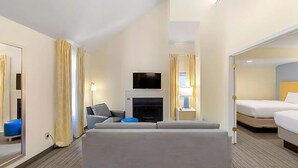 A hotel room with a sofa, a TV, a fireplace, and a bed. - Sonesta ES Suites Cincinnati - Sharonville West (Sharonville)