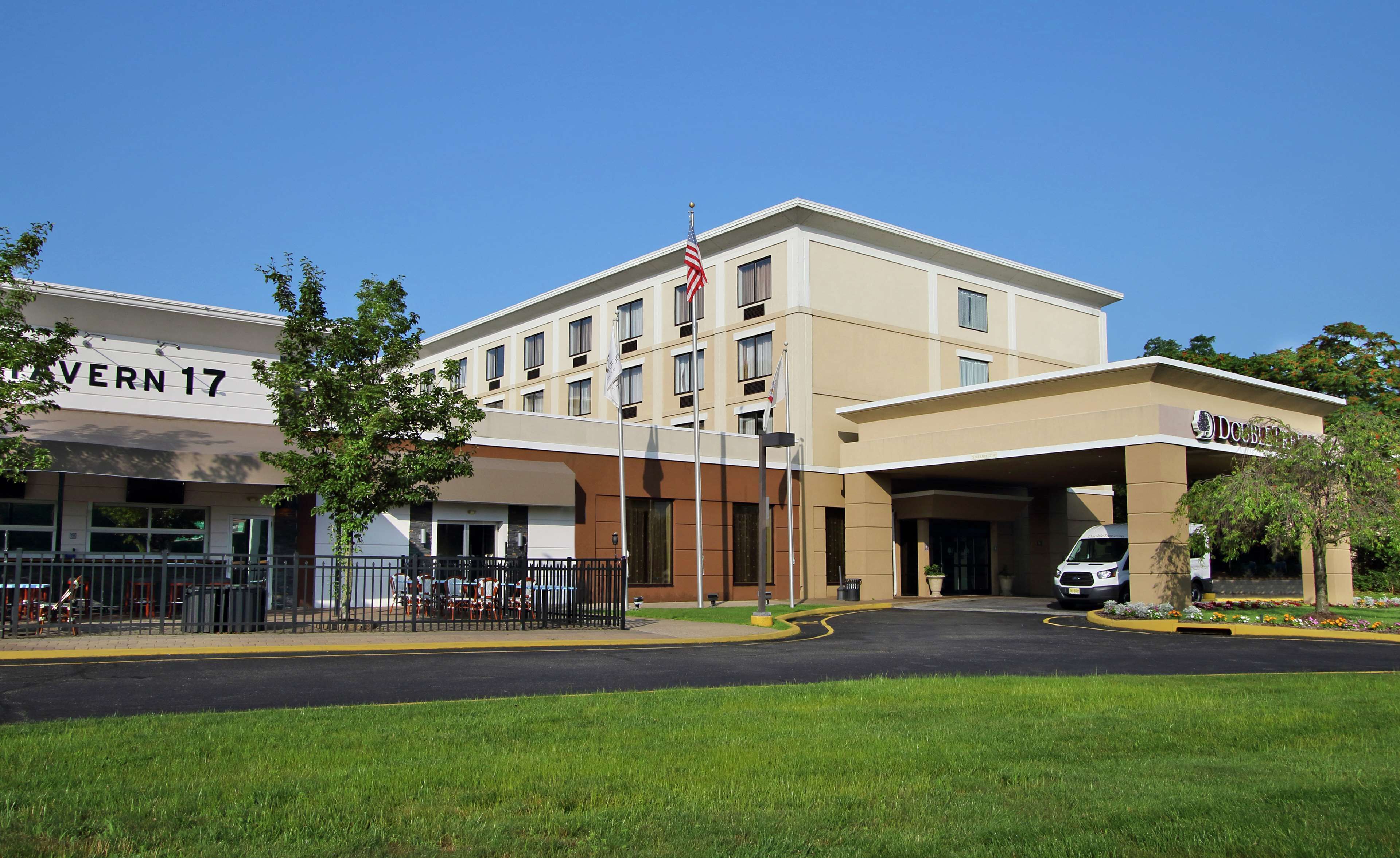 A hotel with a flat facade, multiple windows, and a flagpole with an American flag.