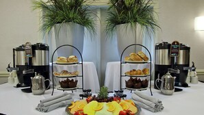 Un bufé de desayuno con cafeteras, pasteles y fruta.
