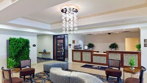 Un hall con mostrador de recepción, zona de estar y una lámpara decorativa.