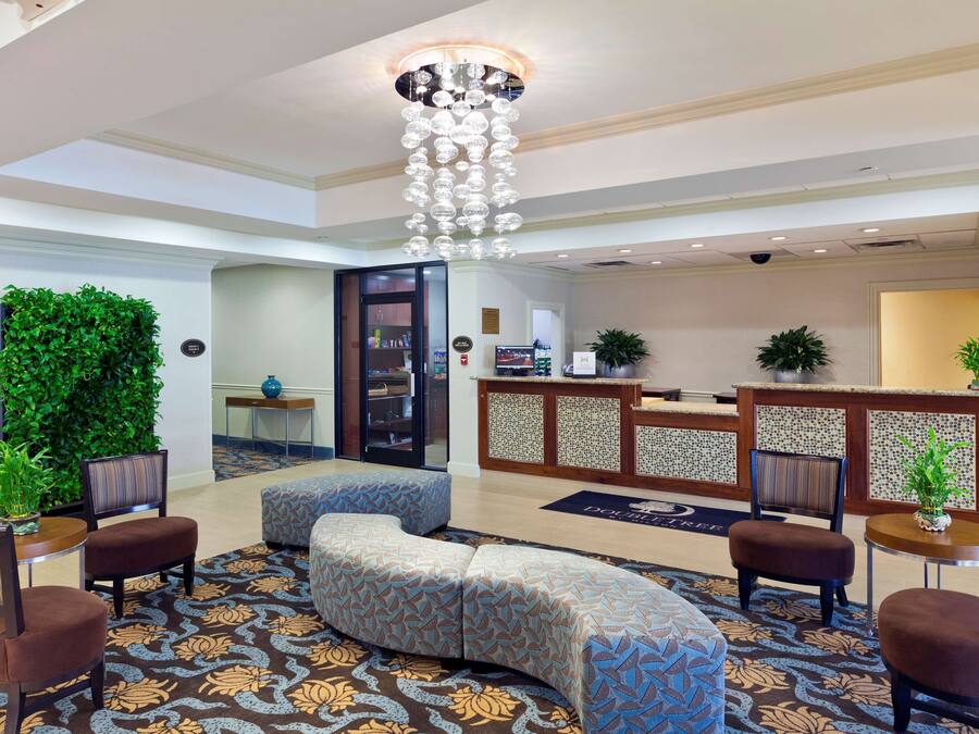 A lobby with a reception desk, seating area, and a decorative chandelier.