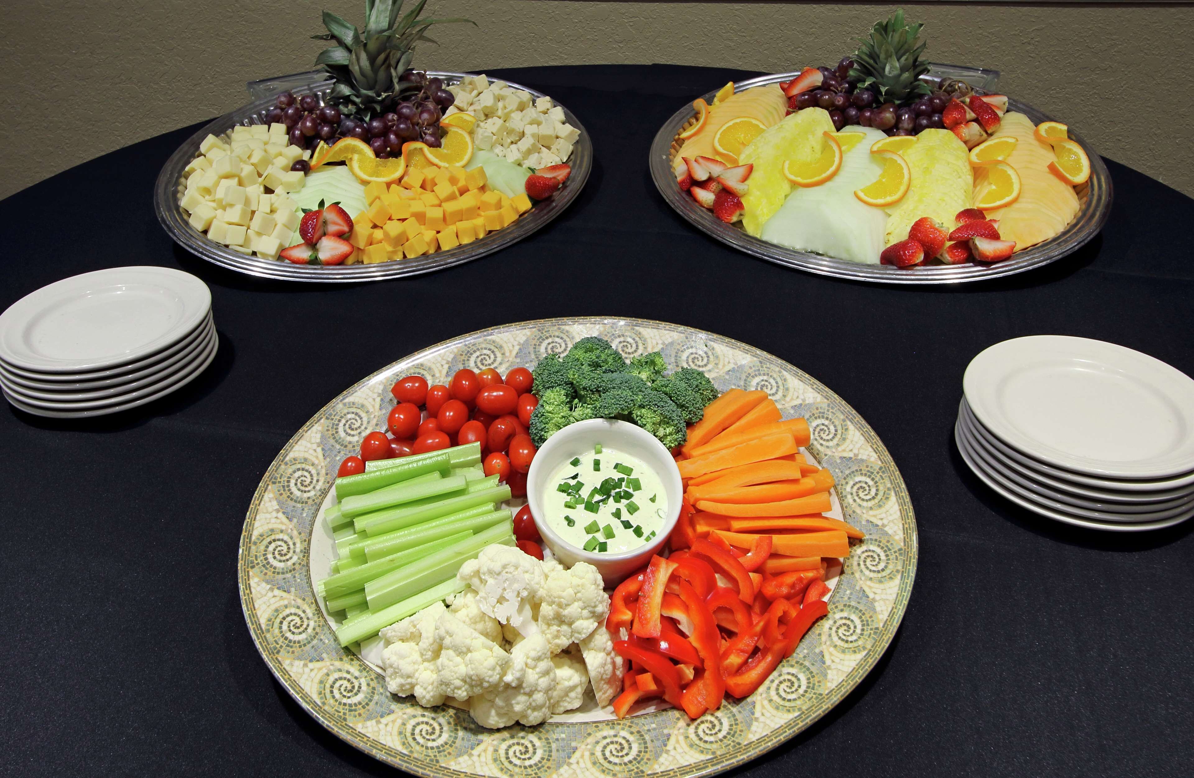 A table with three fruit platters and a vegetable platter with dip.