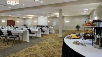 A conference room with tables set for a meeting, a whiteboard, and a buffet area with pastries and coffee.