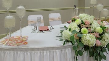Ein Bankettisch mit weißer Tischdecke, rosa Servietten und einer floralen Tischdekoration.
