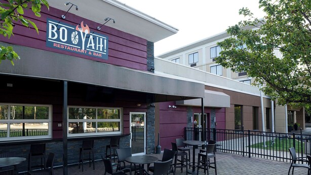Un área de estar al aire libre con mesas y sillas en un restaurante llamado BOYAH!