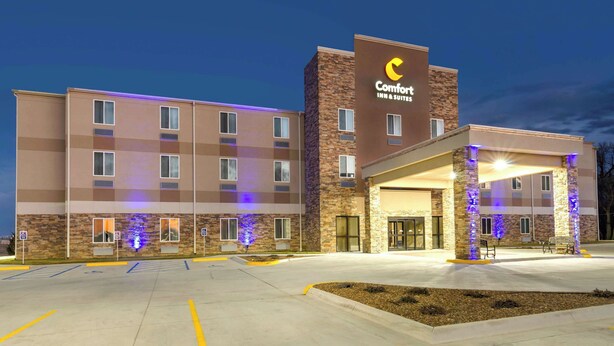 Um hotel Comfort Inn & Suites com design moderno, destacando uma entrada imponente e um estacionamento.