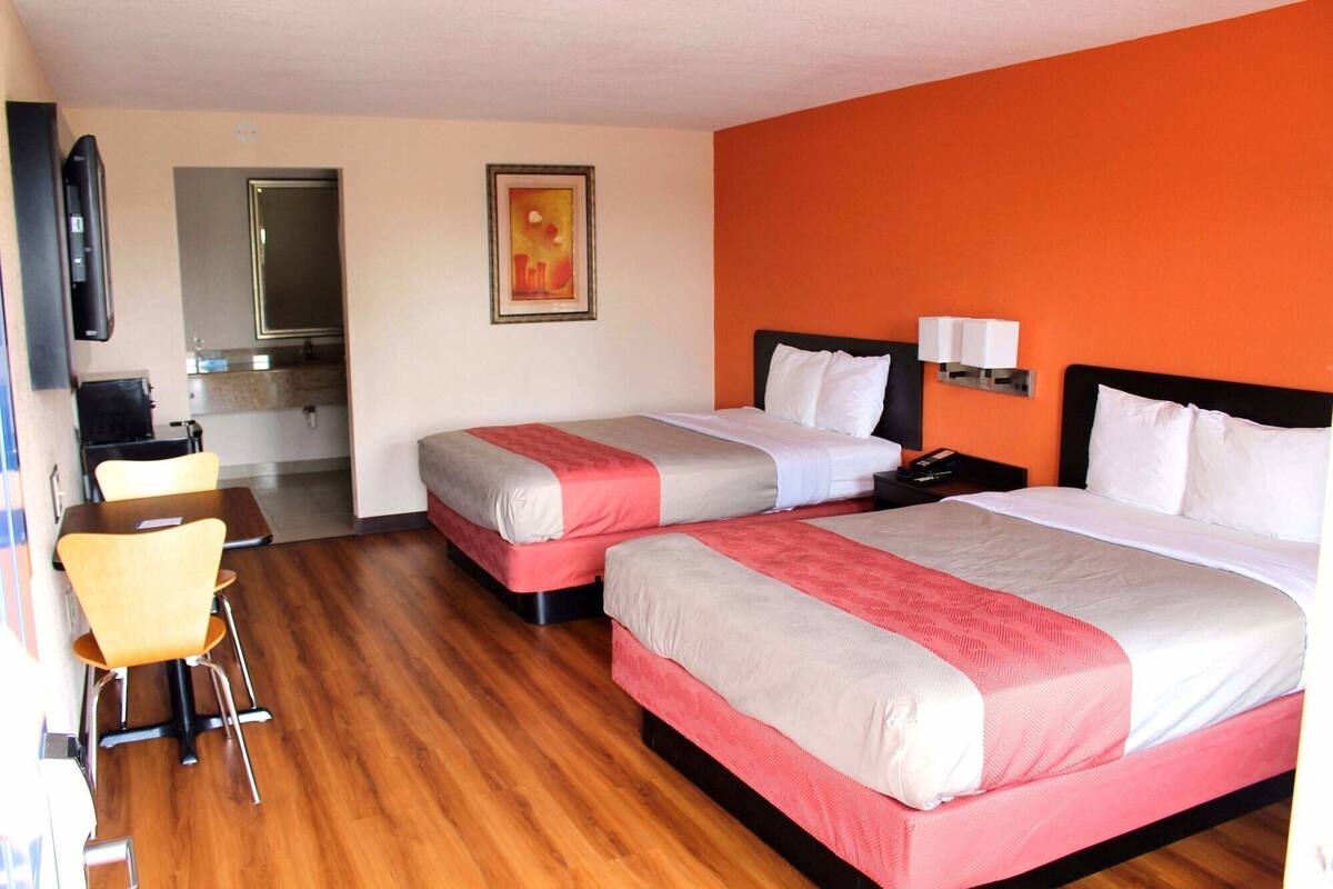 A hotel room with two beds, a desk, and a chair.