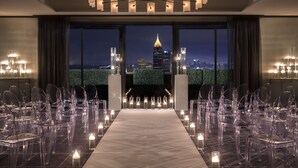 A conference room with a long table, clear chairs, candles, and a view of a cityscape at night.