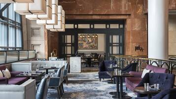 A spacious lobby with seating areas, a central bar, and a large chandelier.