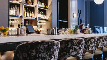 A bar area with multiple shelves of bottles, a bar counter, and several bar stools.