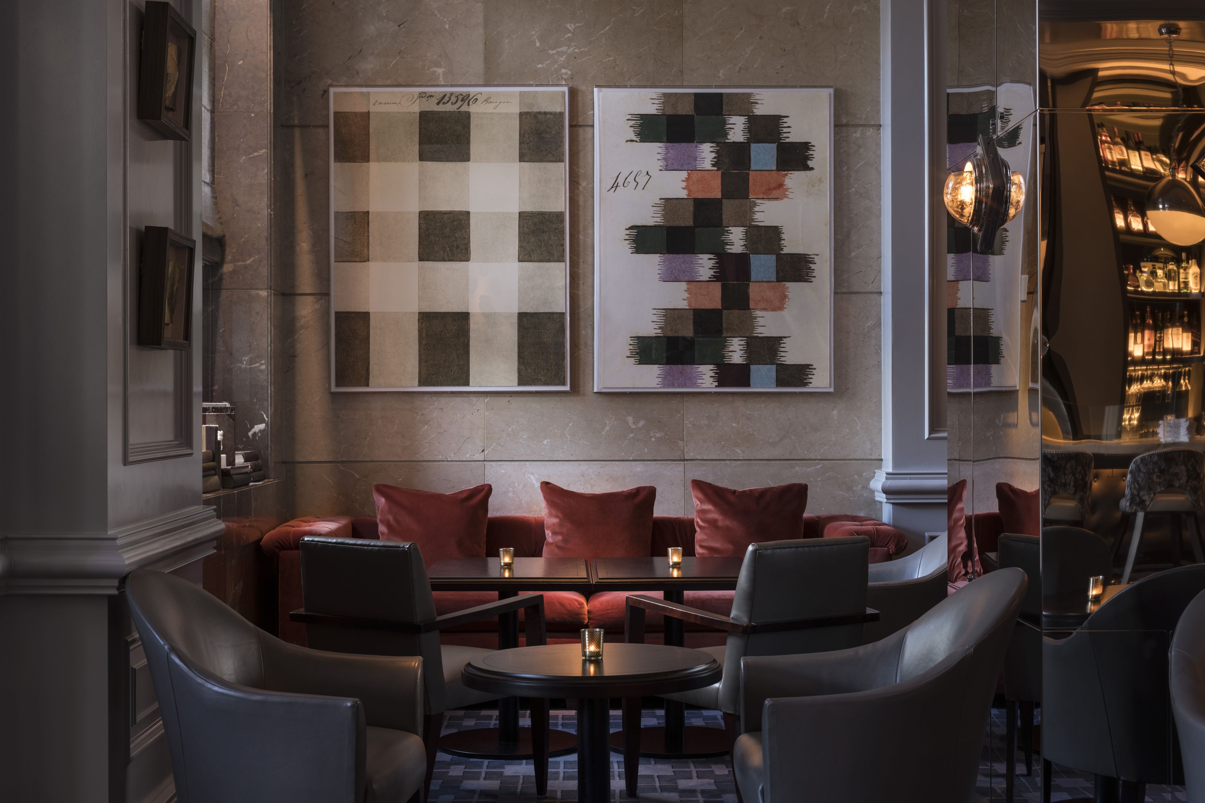 A modern lounge area with leather sofas, round tables, and framed artwork on the wall.