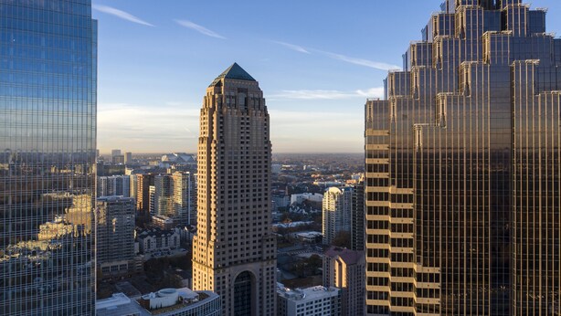 A high-rise building with a distinctive architectural style, surrounded by other tall buildings in an urban setting.