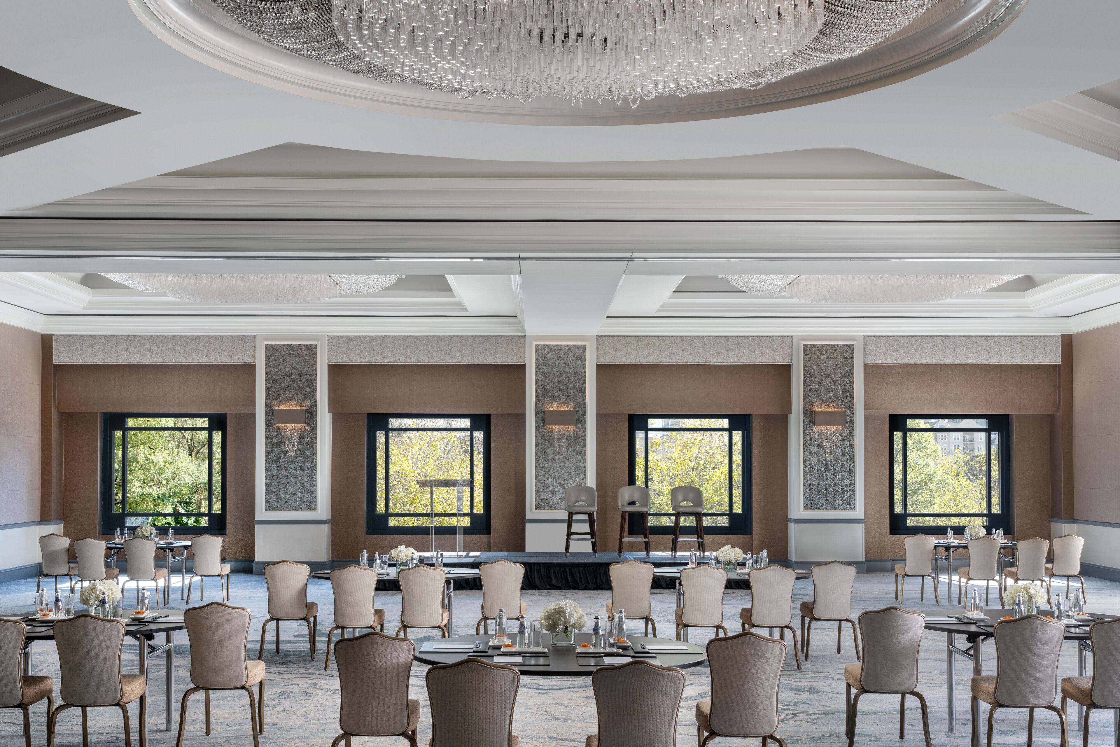 A conference room with a stage, large windows, and a chandelier.