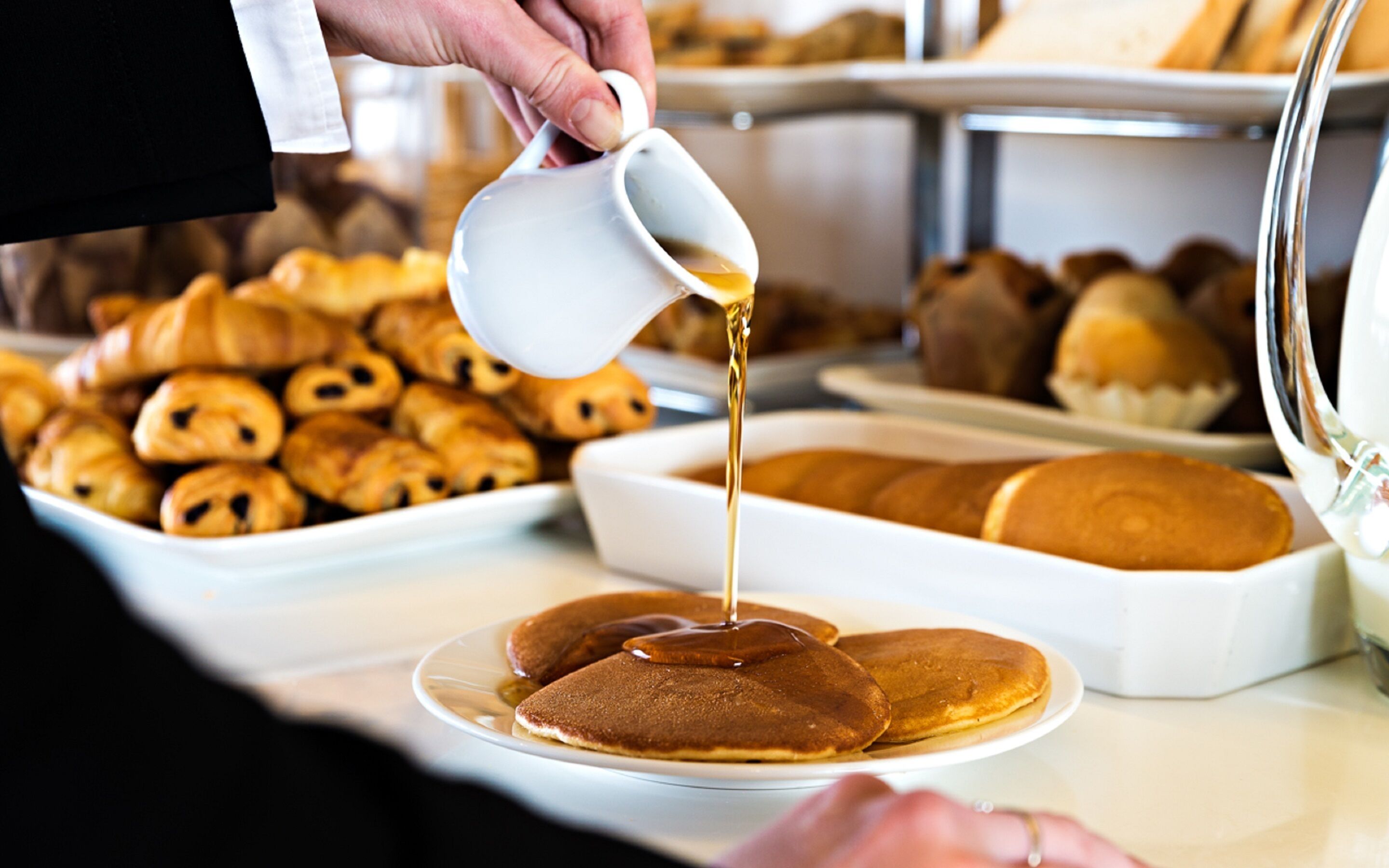 A breakfast buffet with pancakes and pastries.