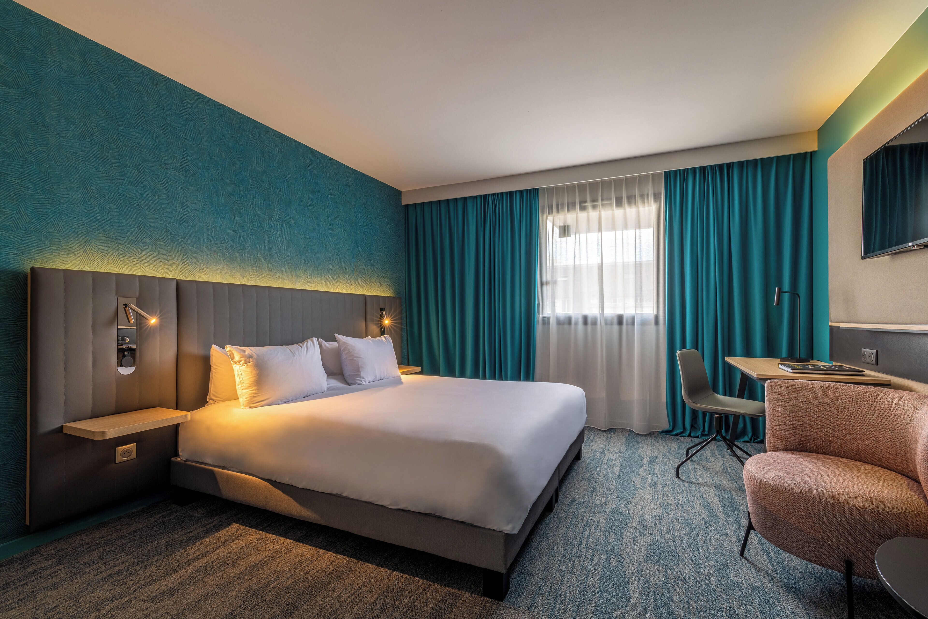 Una habitación de hotel con una cama grande, un escritorio, una silla y un televisor.