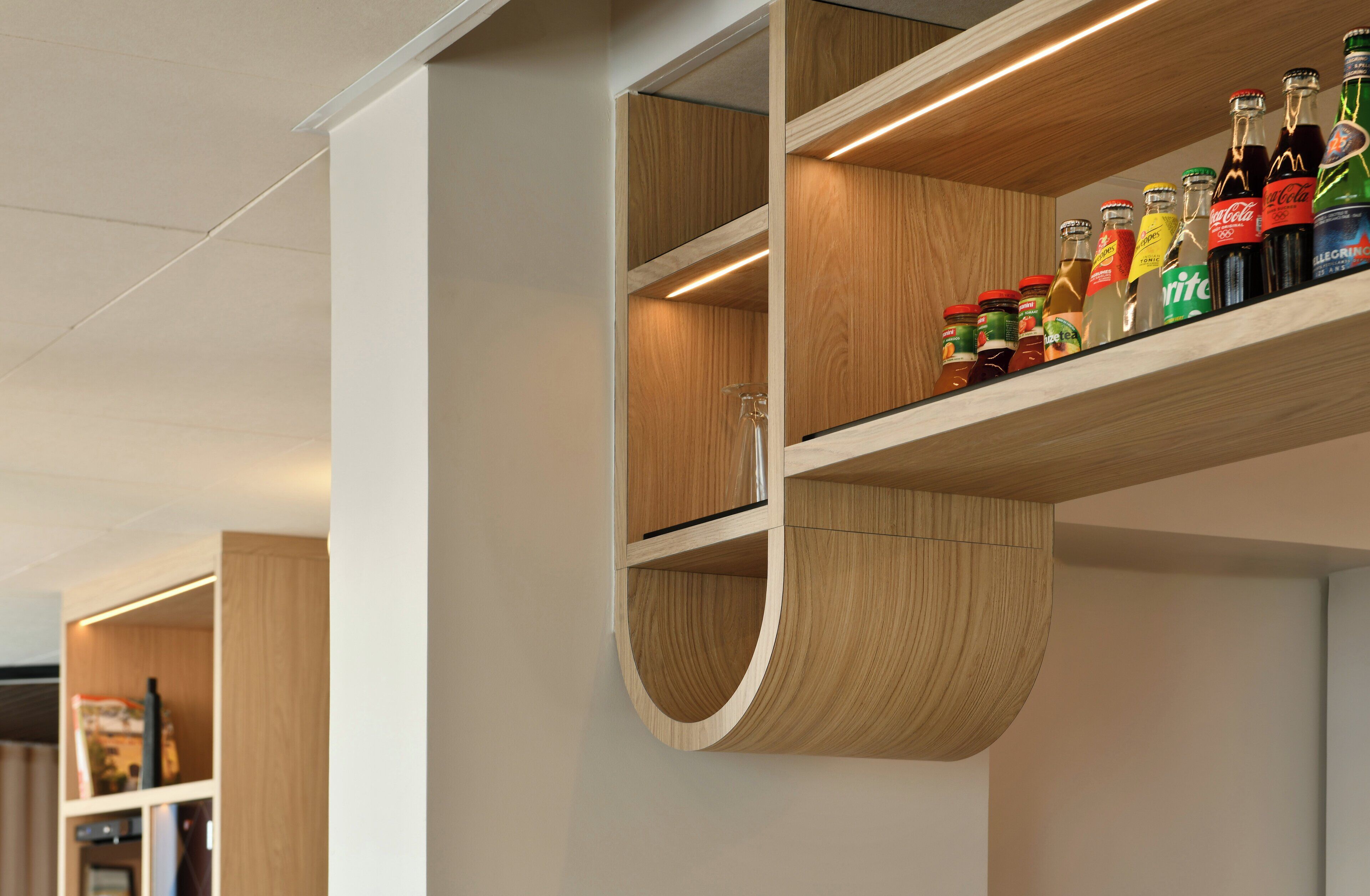 Un interior moderno con estanterías de madera que exhiben diversas botellas.