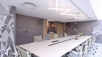 A conference room with a long table, chairs, and a modern ceiling design.
