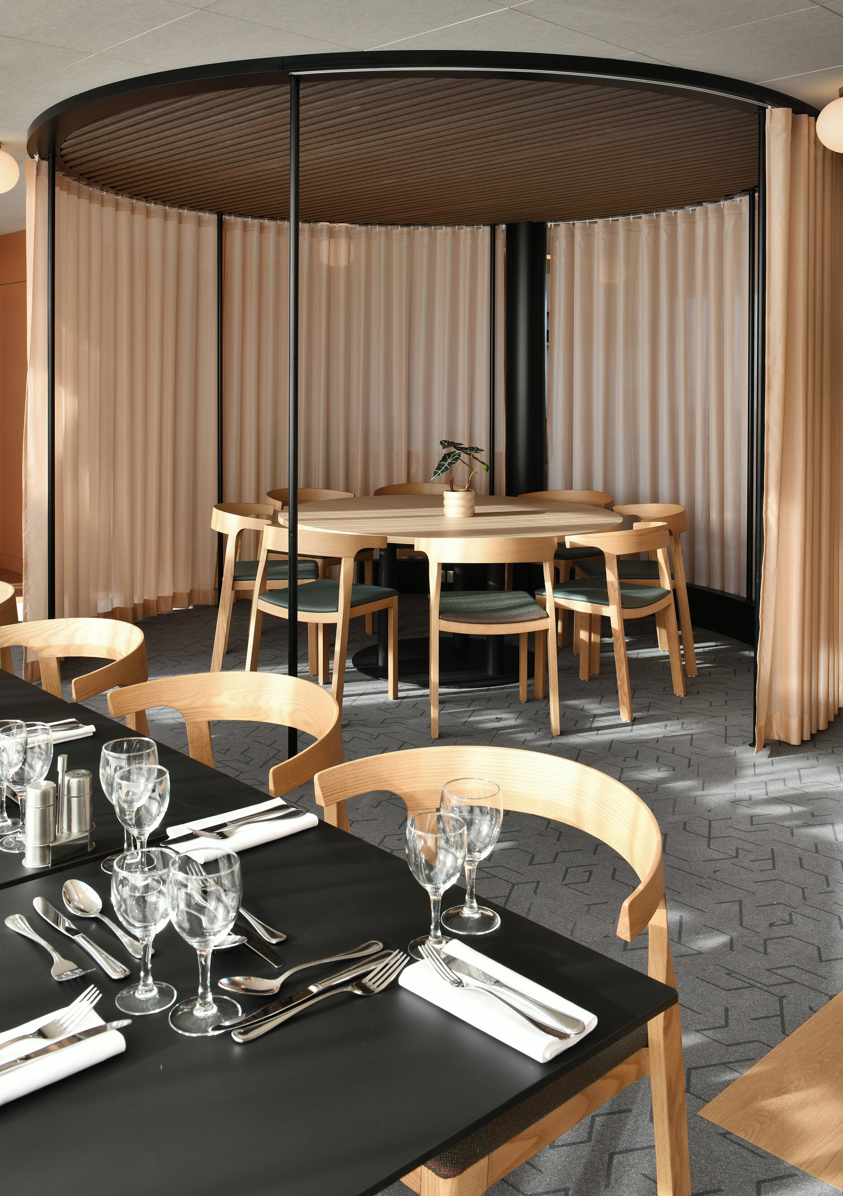 Un moderno comedor con una mesa redonda y sillas, mantel negro y una planta en maceta sobre la mesa.