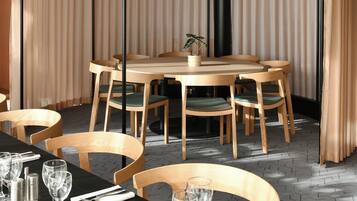 Un moderno comedor con una mesa redonda y sillas, mantel negro y una planta en maceta sobre la mesa.