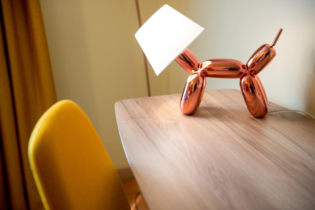 A table with a metallic sculpture and a white lamp.