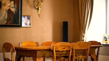 Un coin repas avec une table et des chaises en bois, un tapis à motifs, un tableau et un chandelier fixé au mur.
