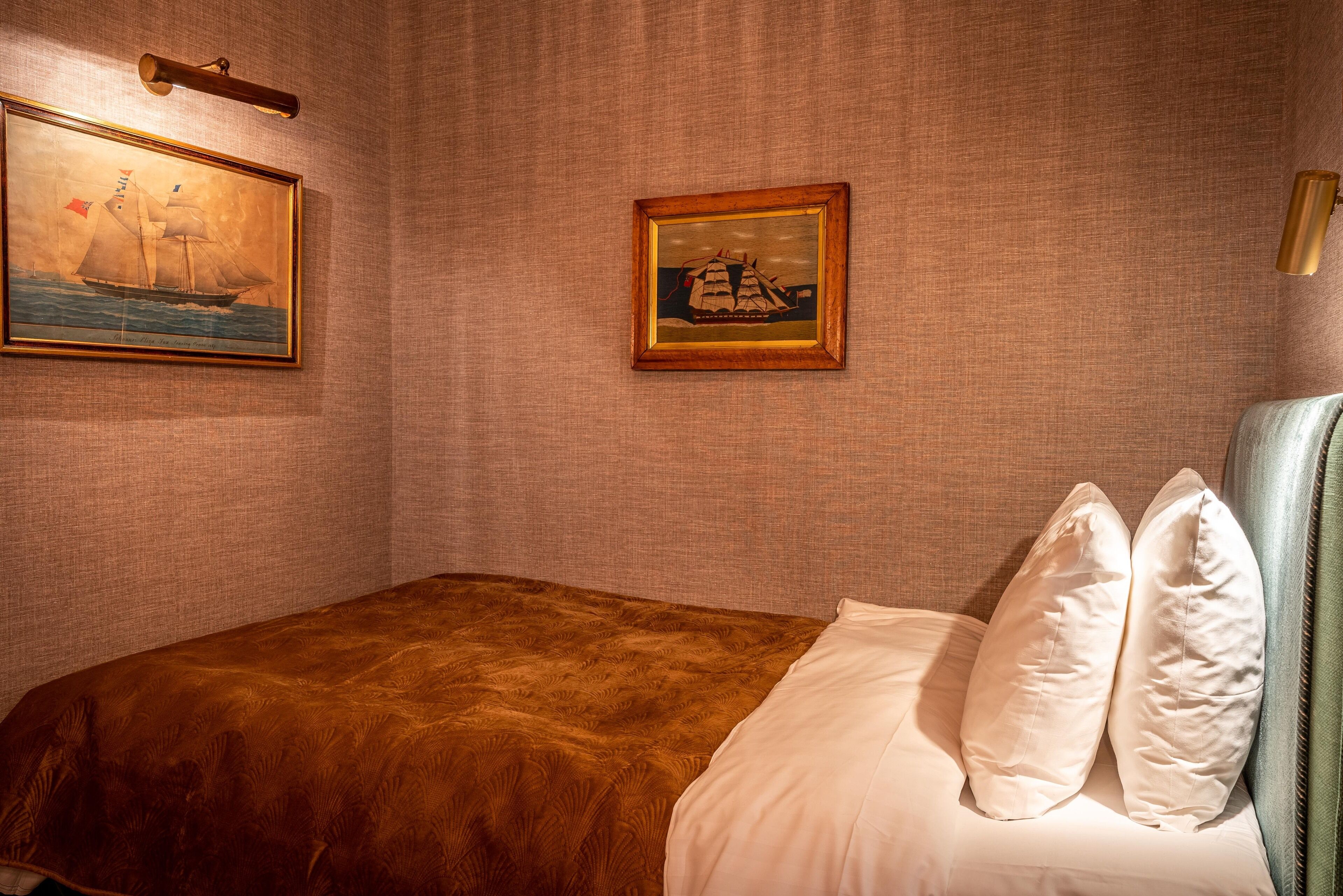Un dormitorio con una cama, almohadas y dos cuadros en la pared.