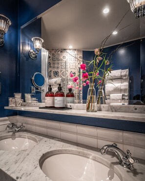 Un baño con dos lavamanos, un espejo grande y un jarrón decorativo con flores.