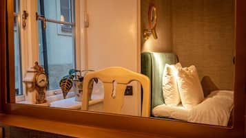 Una habitación de hotel con una cama, una mesita de noche, un espejo, un reloj y una ventana.