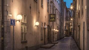 Rua de calçada com edifícios históricos, incluindo um hotel com uma placa que indica ser um estabelecimento 'TO BE D'.