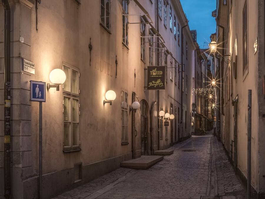 Rua de calçada com edifícios históricos, incluindo um hotel com uma placa que indica ser um estabelecimento 'TO BE D'.