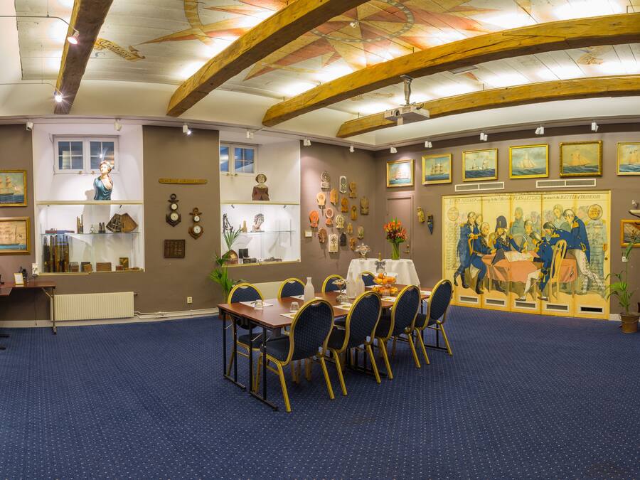 Un comedor con una mesa redonda, sillas y un mural en la pared.