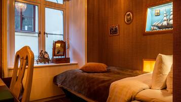 Ein Schlafzimmer mit einem Bett, einem Sessel, einem Fenster und einem Bild an der Wand.