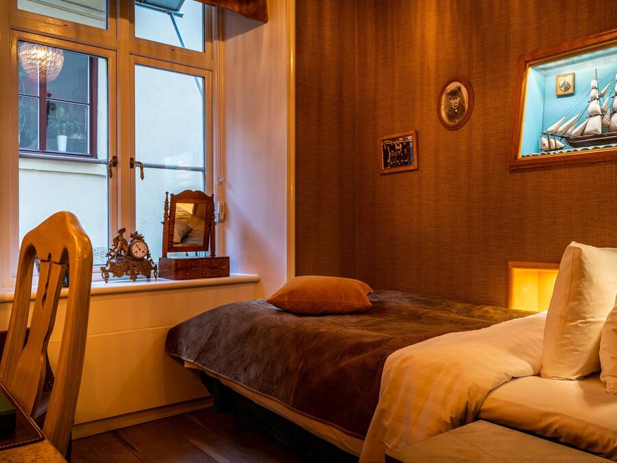 Ein Schlafzimmer mit einem Bett, einem Sessel, einem Fenster und einem Bild an der Wand.