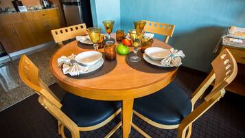 Une table à manger avec des chaises, une cuisine en arrière-plan et un mur bleu.